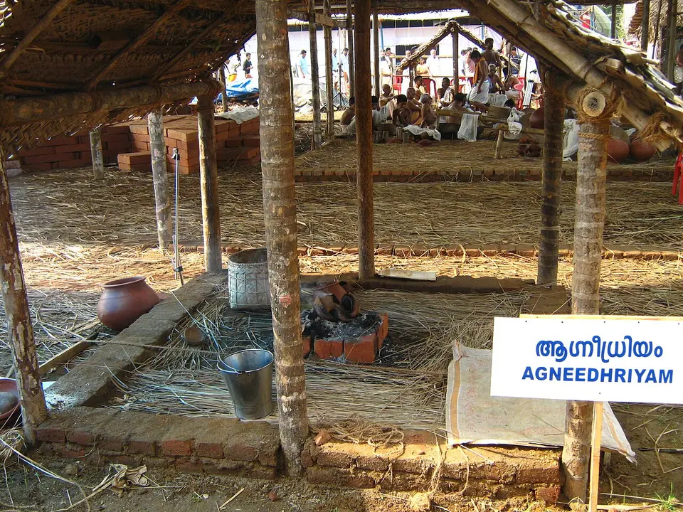 The Agnidhriya fire enclosure under a thatched shed at a modern Nambudiri Vedic fire ritual in Kerala, marked with a sign reading Agneedhriyam