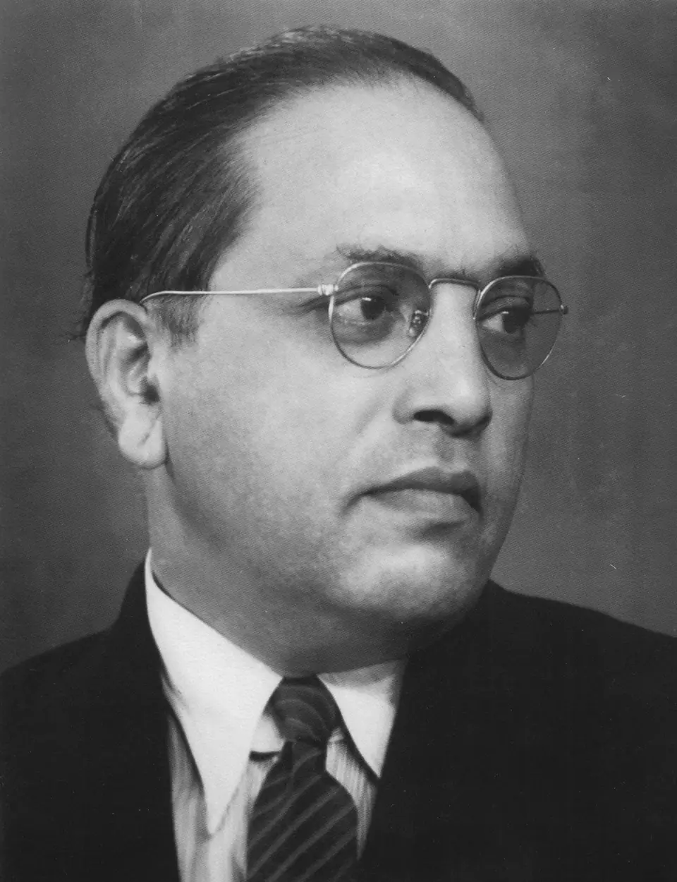 Black-and-white portrait of B. R. Ambedkar in round glasses, suit and tie