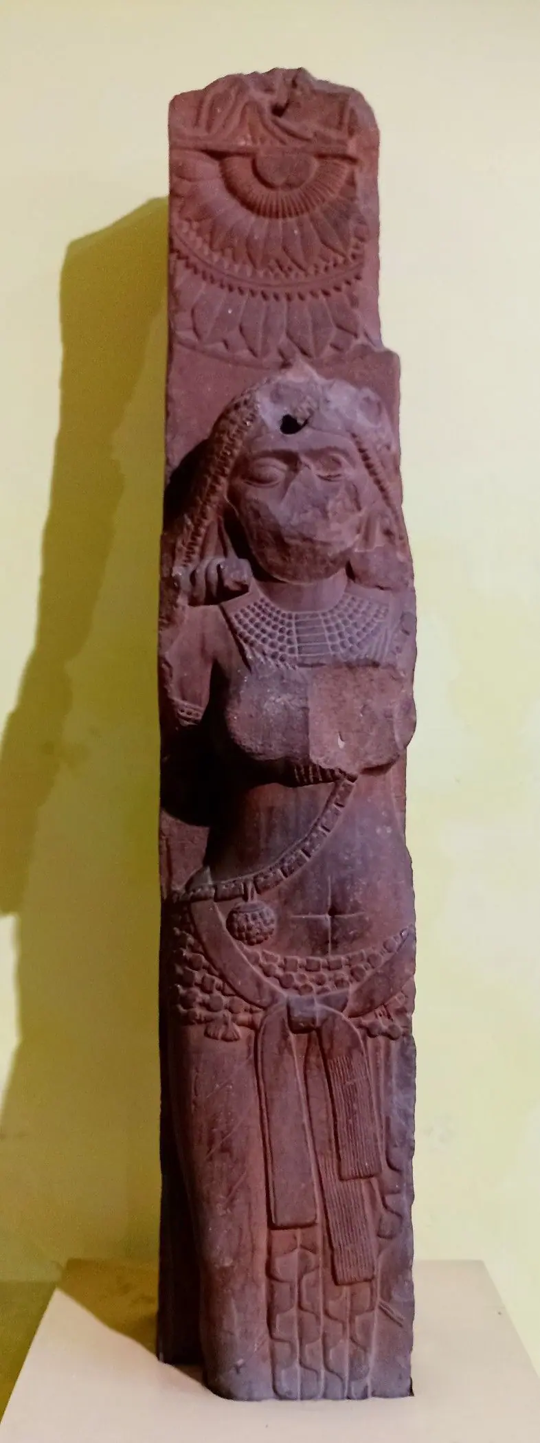 Red sandstone railing post from Bharhut carved with a standing yakṣī wearing a heavy necklace and girdle, under a lotus medallion