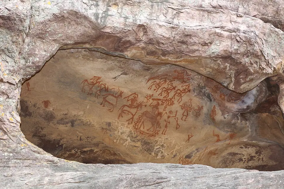 Red ochre paintings of animals and human figures on the overhanging rock face of Shelter 8 at Bhimbetka, central India