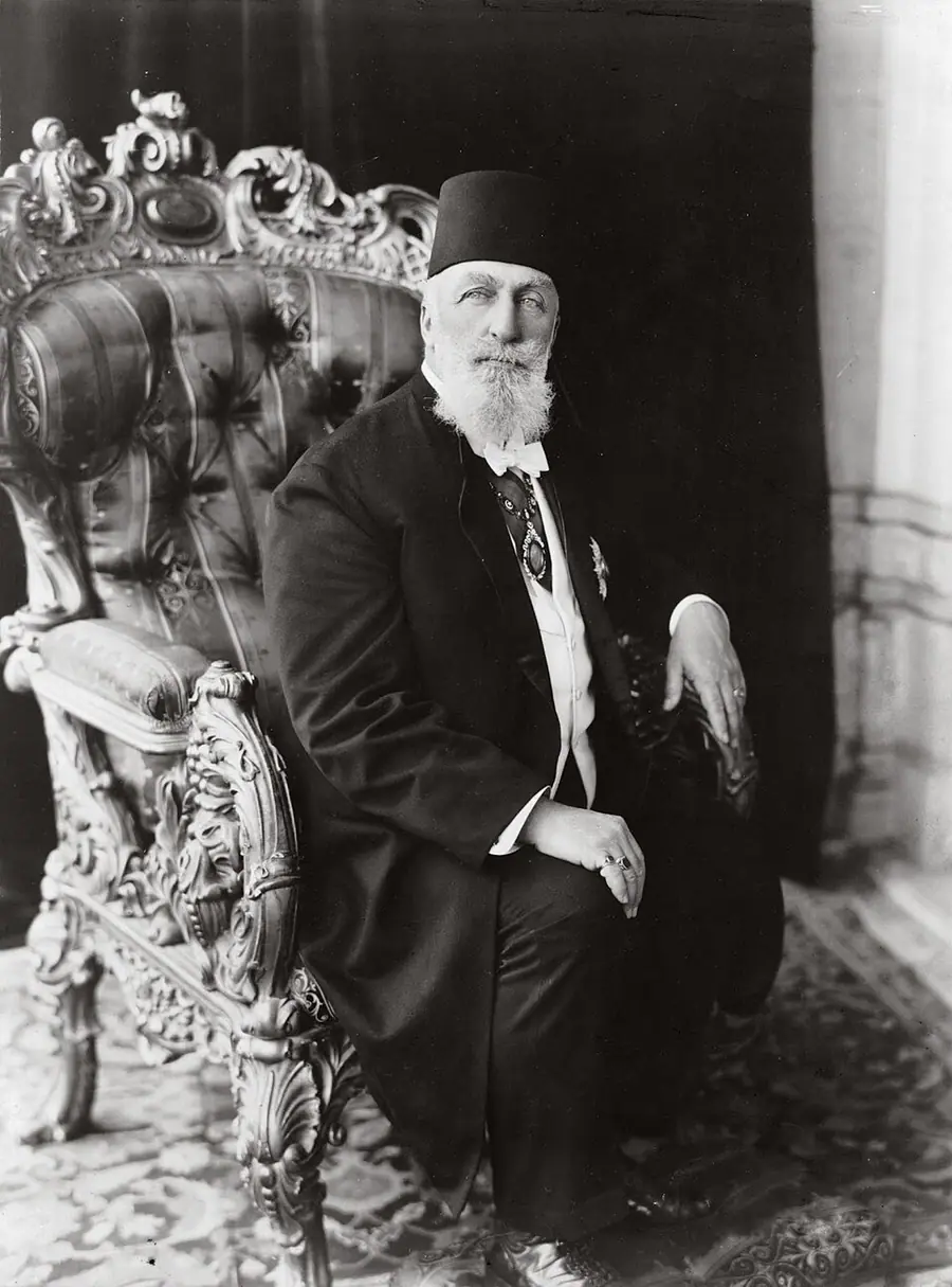 A photograph of ʿAbd al-Majīd II, the last Ottoman caliph, seated in an ornate chair, wearing a fez and a dark suit