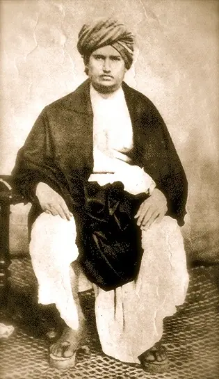 Sepia photograph of Dayananda Saraswati seated, wearing a turban and a dark shawl
