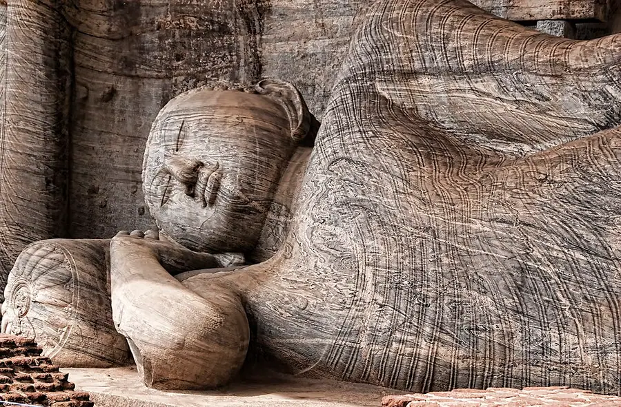 Head and shoulder of the colossal recumbent Buddha at Gal Vihara, carved from banded grey granite, resting on a cylindrical pillow