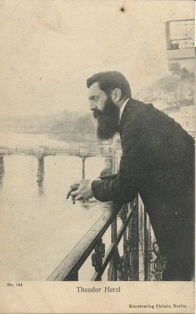 Theodor Herzl leaning on the railing of a hotel balcony above the Rhine in Basel, in a long dark coat, looking out over the river