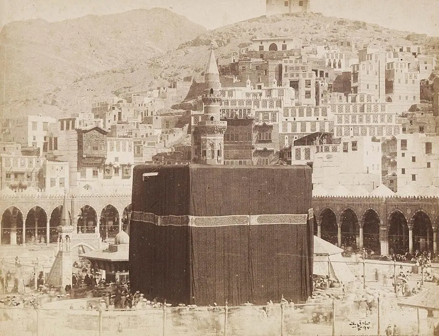 An early photograph of the Kaaba in Mecca, about 1880, draped in black inside the colonnaded court, with houses on the hills beyond