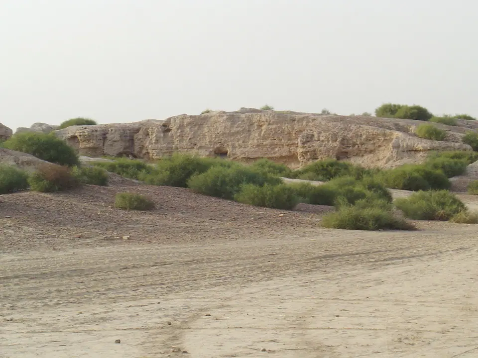 The eroded western mound at Kalibangan, Rajasthan, with scrub and a sandy track