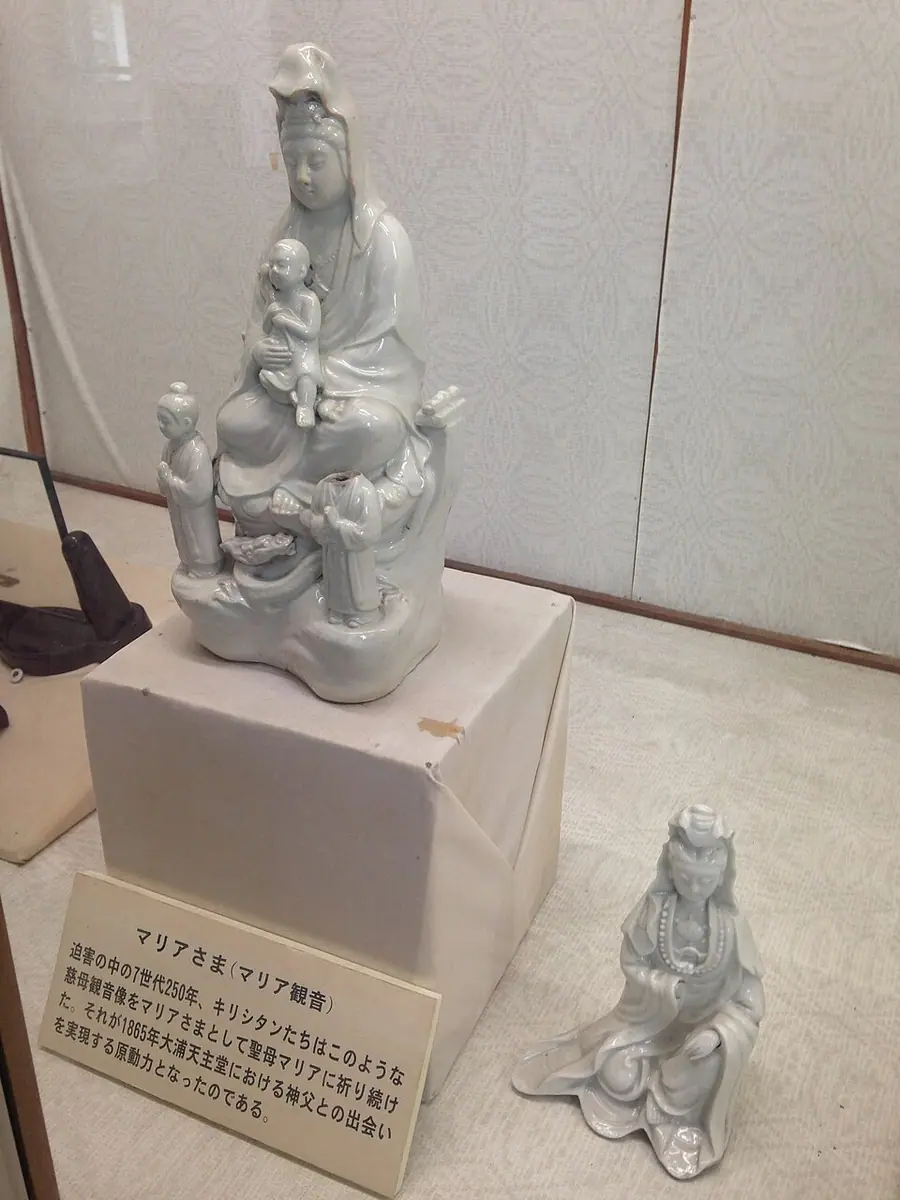 Two white porcelain figures of the bodhisattva Kannon in a museum case, the larger holding a child, venerated by Japan's hidden Christians as Mary