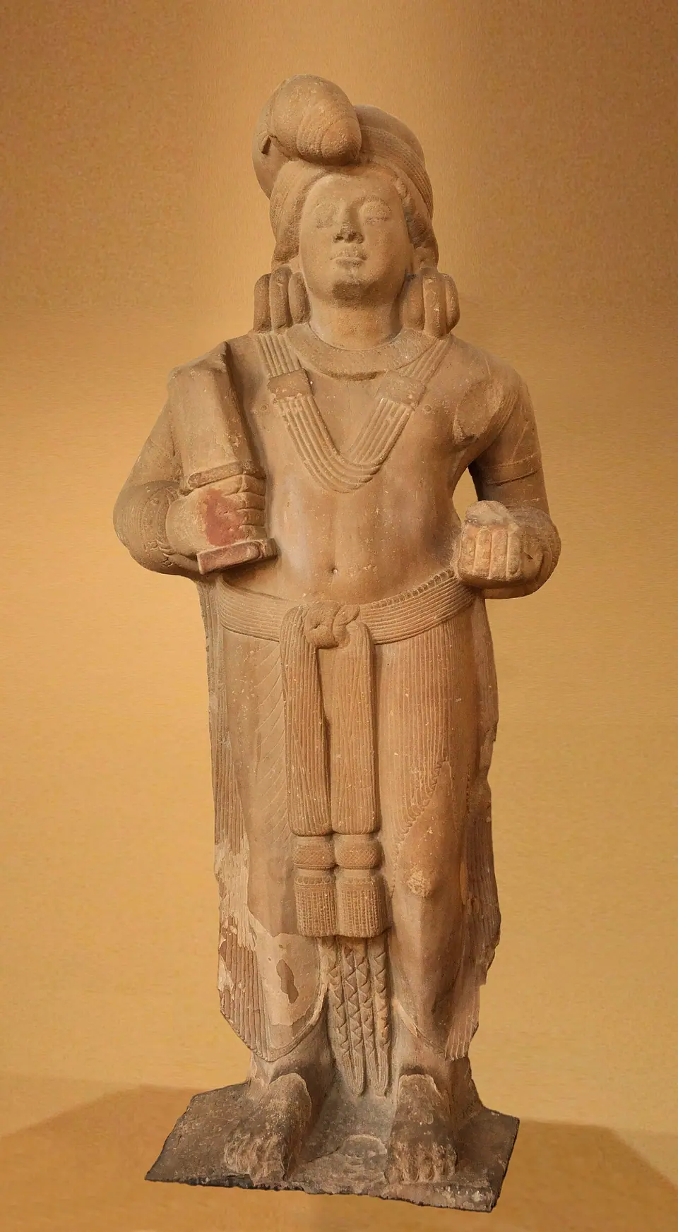 Red sandstone standing yaksha figure from Mathura holding a club