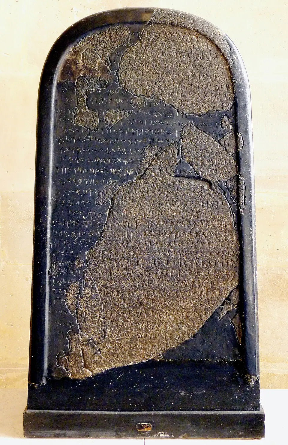 The black basalt Mesha Stele with its rounded top and lines of Moabite script, in the Louvre