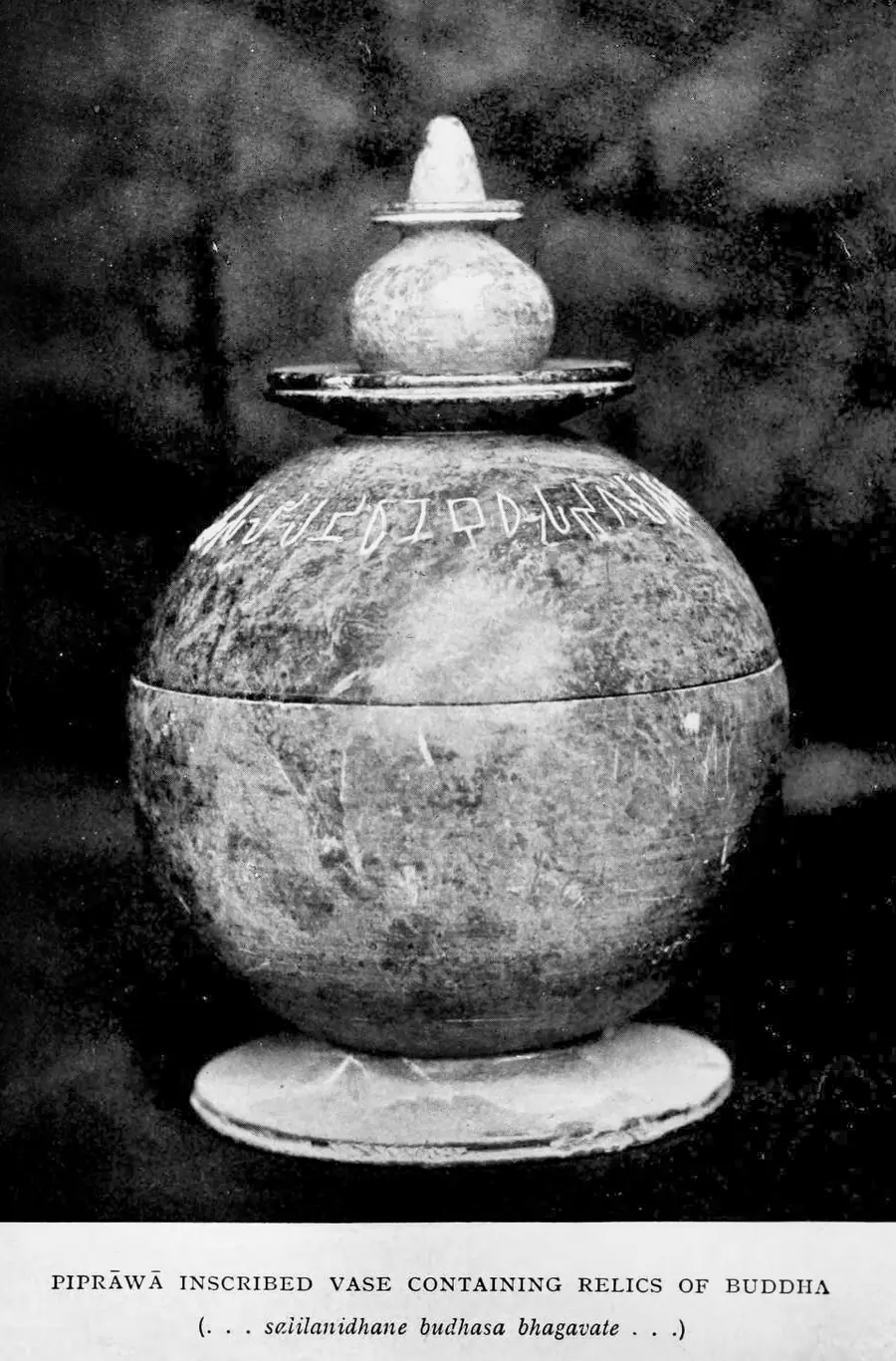 Round soapstone reliquary with a knobbed lid, a line of Brāhmī letters incised around its shoulder, photographed after its 1898 excavation at Piprahwa