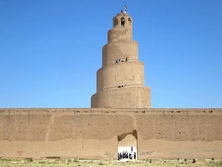 The spiral Malwiya minaret of the Great Mosque of Samarra rising behind the mosque's long brick wall