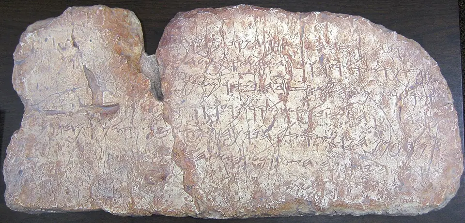 A pale limestone slab broken in two, incised with six lines of Old Hebrew script