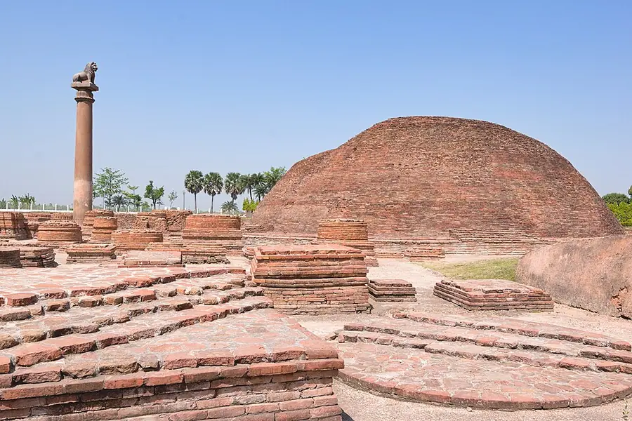 The large brick stupa at Kolhua, Vaishali, with Ashoka's lion pillar standing to its left and the foundations of smaller votive stupas in front