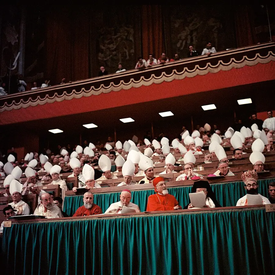 Bishops in white mitres filling tiered seating in St Peter's Basilica during a session of the Second Vatican Council, with prelates in red at the front